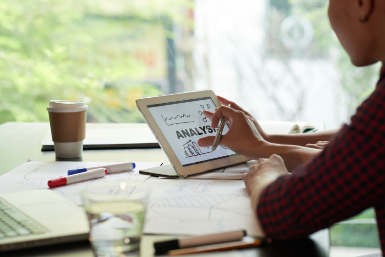 Author writing book manuscript surrounded by research notes and AI writing tool interface